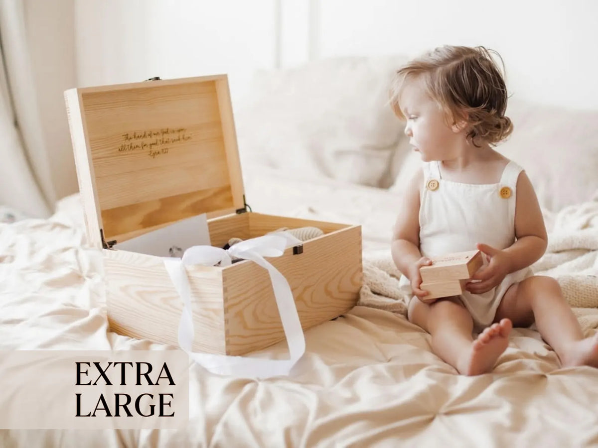 Extra large personalized wooden baby keepsake box with ribbon detail displayed beside a baby.